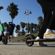 People ride Lime shared dockless electric scooters along Venice Beach on August 13, 2018 in Los Angeles, California.